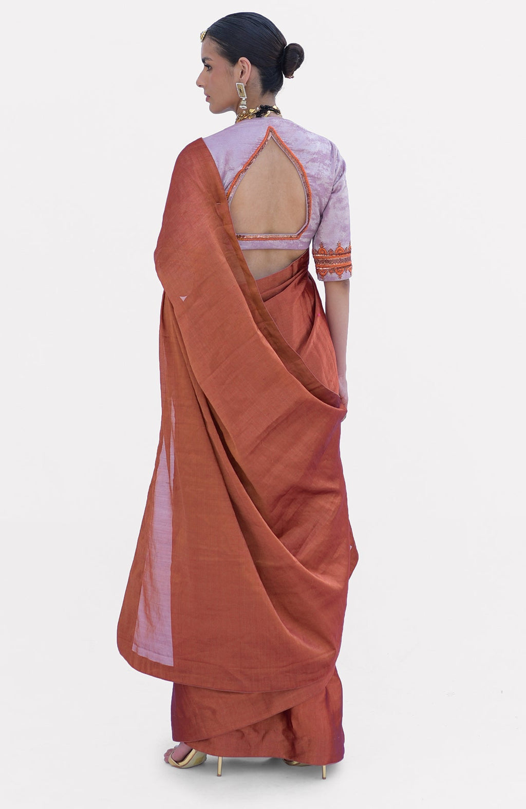 A woman models a pre-stitched copper tissue saree with a zardozi embroidered pink blouse.