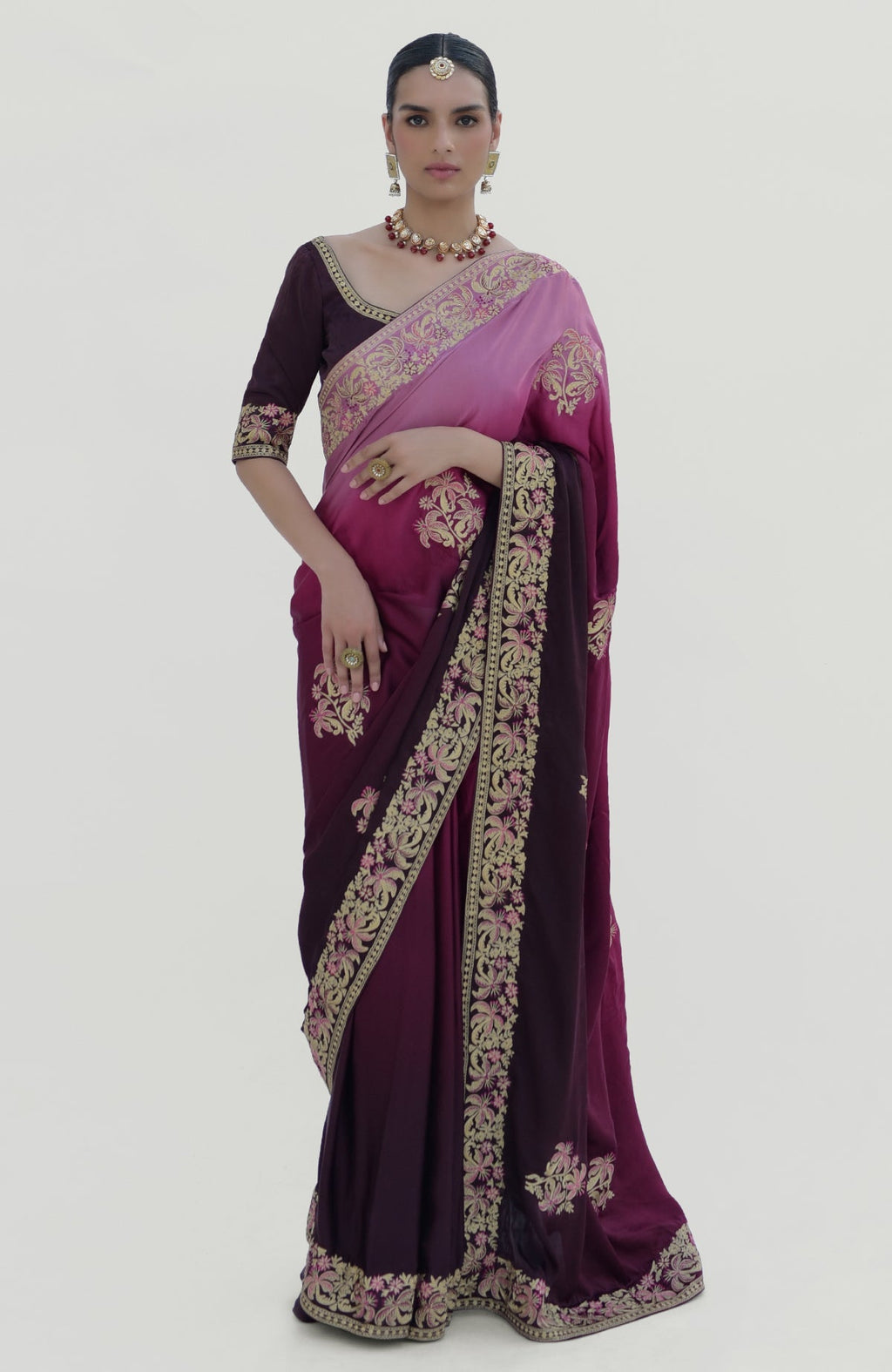A woman models a wine-pink ombre Kashidakari embroidered saree set with a matching blouse.