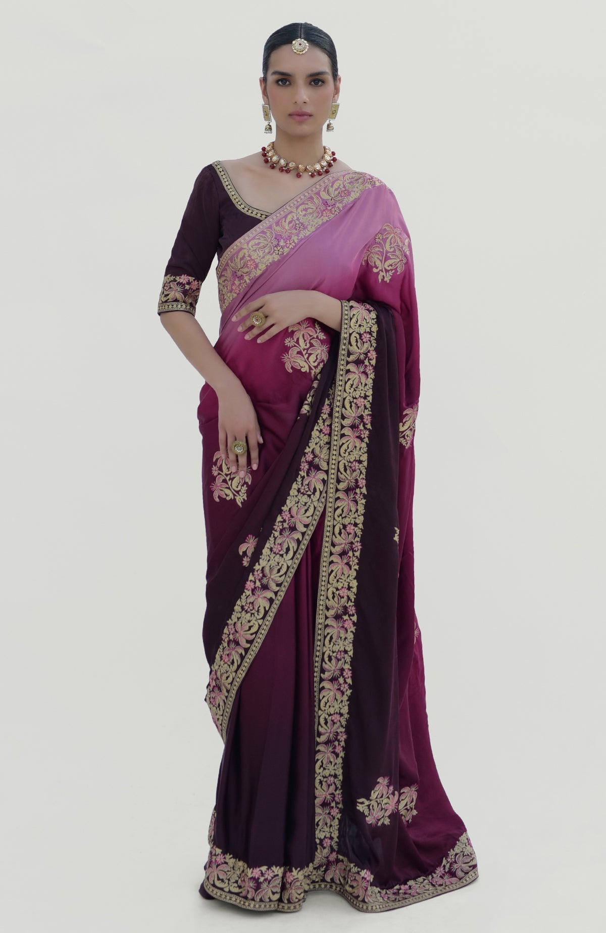 A woman models a wine-pink ombre Kashidakari embroidered saree set with a matching blouse.
