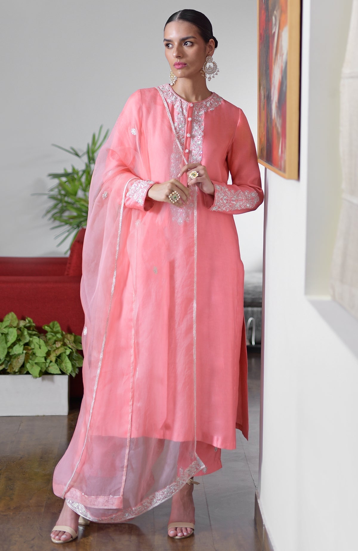 A woman models a flamingo pink hand-embroidered chikankari suit set with a sheer dupatta.