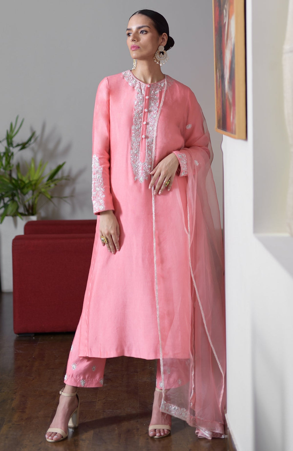 A woman models a flamingo pink hand-embroidered Chikankari suit set with a sheer dupatta.
