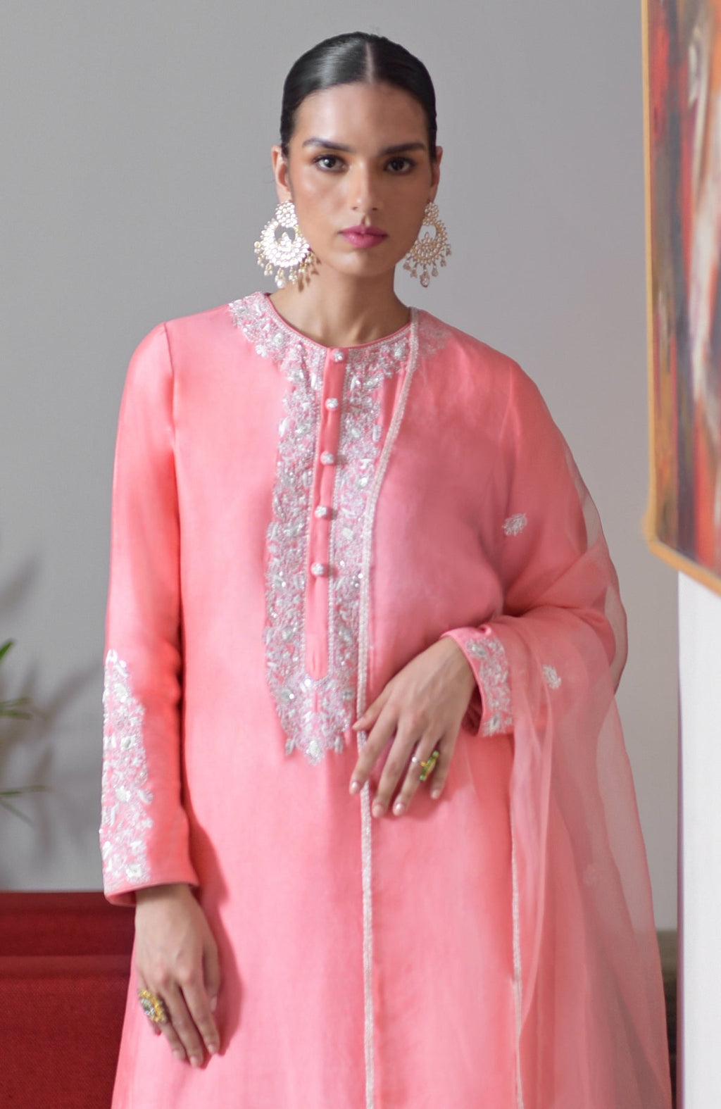 A woman models a flamingo pink hand-embroidered chikankari suit set with a sheer dupatta.