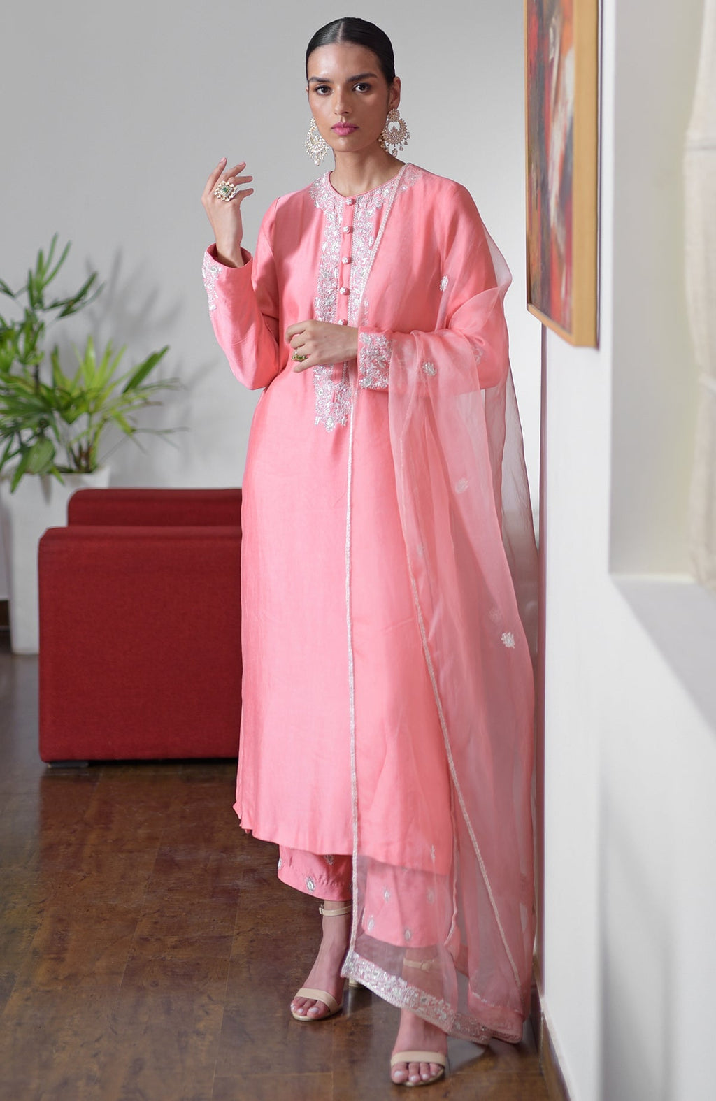 A woman models a flamingo pink hand-embroidered chikankari suit set with a sheer dupatta.