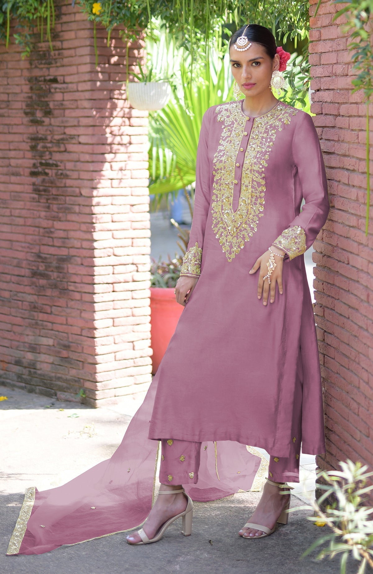 A woman models a mauve kurta set with gold embroidery, matching pants, and a sheer dupatta.