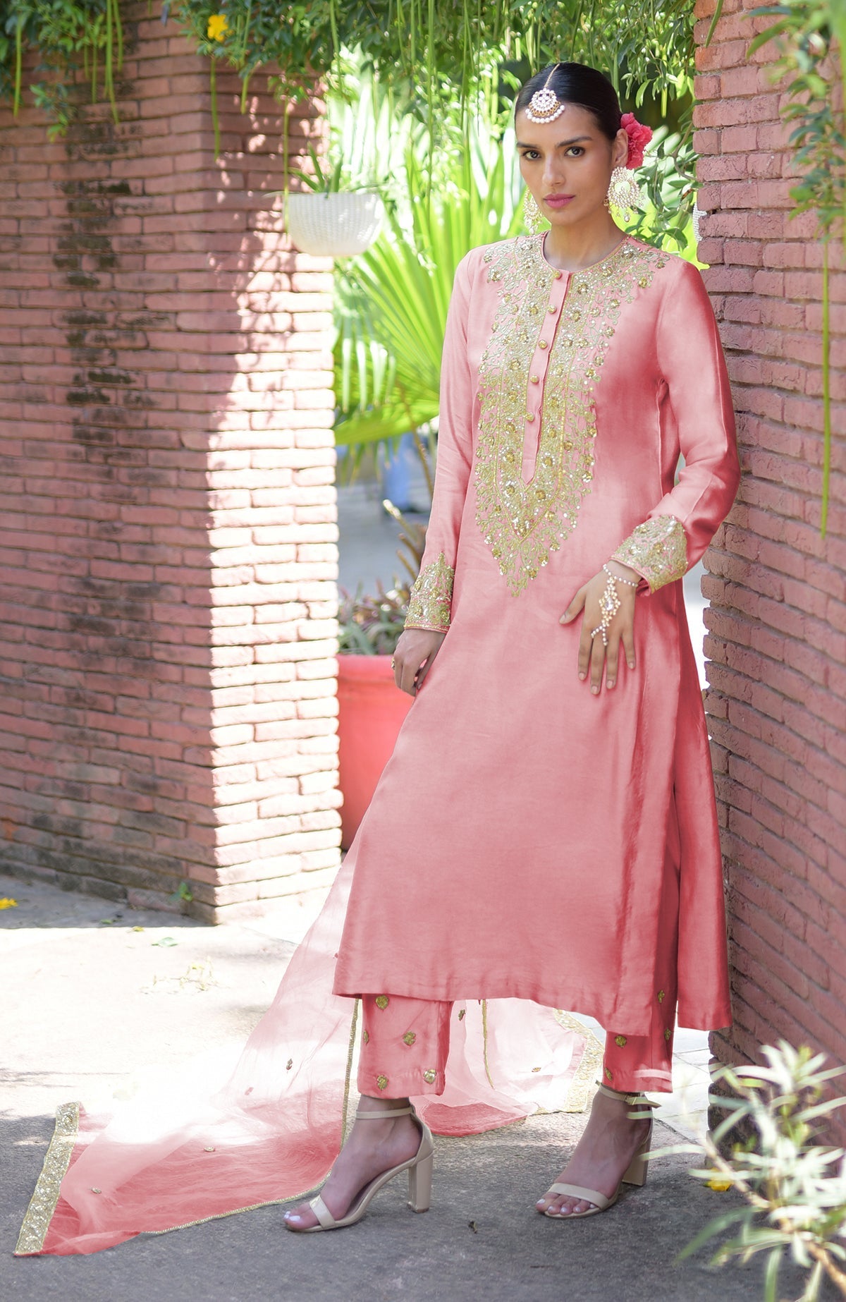 A woman models a pressed rose kurta set with gold embroidery and a matching dupatta.