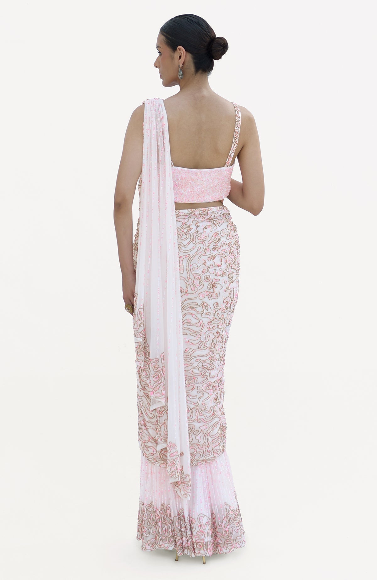 A woman models a white and pink hand-embroidered draped saree set from the back.