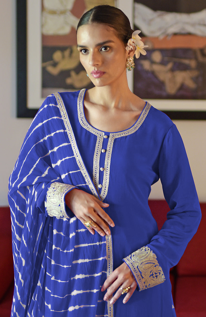 A woman models a royal blue sharara set with white tie-dye and gold embroidery.