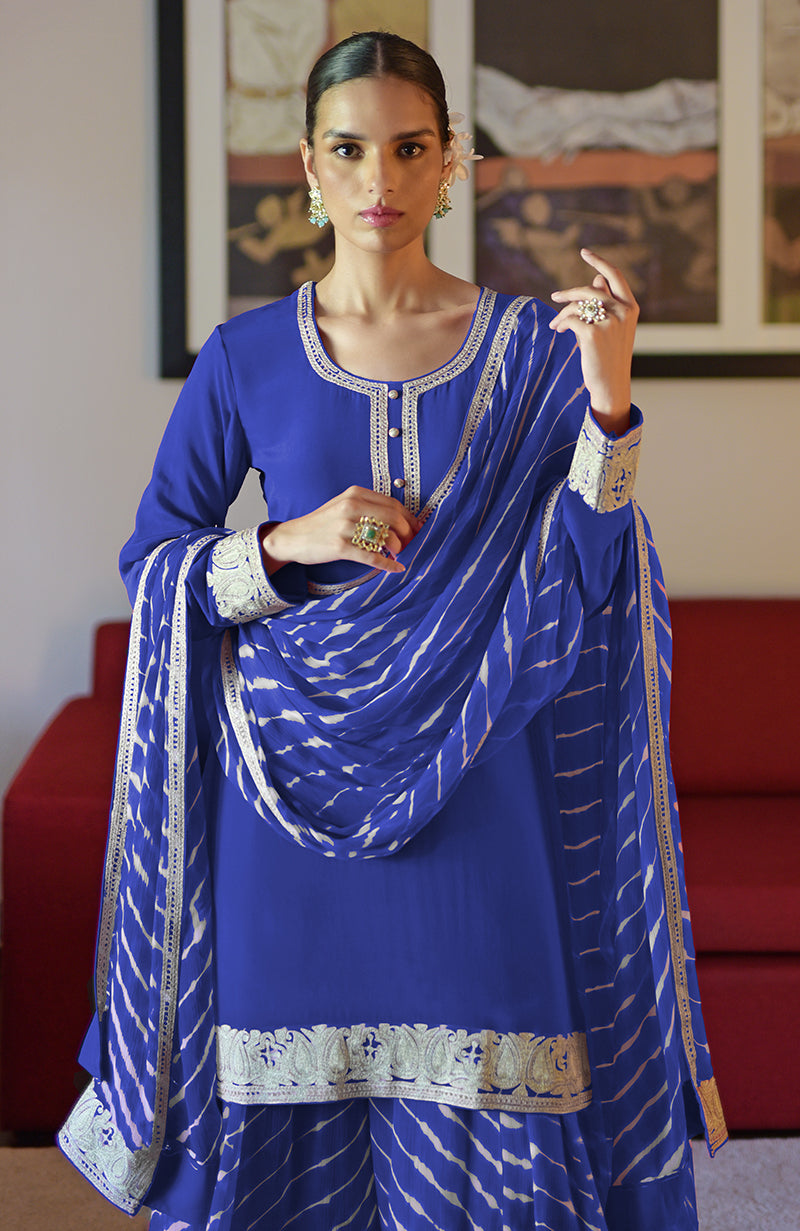 A woman models a royal blue sharara set with silver Kashmiri tilla embroidery.
