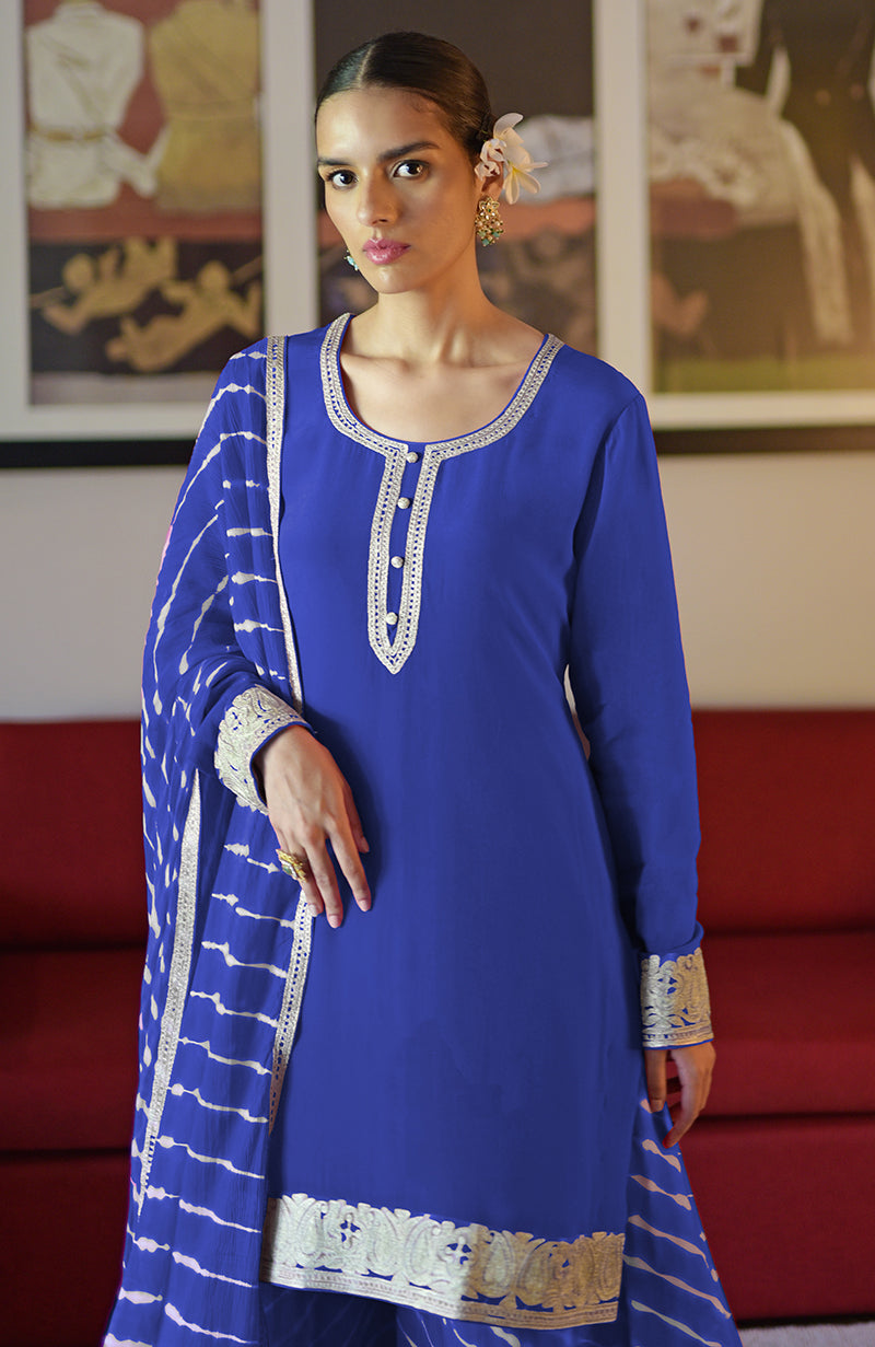 A woman models a royal blue sharara set with silver Kashmiri tilla embroidery.
