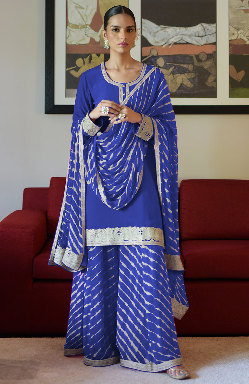 A woman models a blue leheriya handcrafted tie-dye and Kashmiri tilla sharara set.