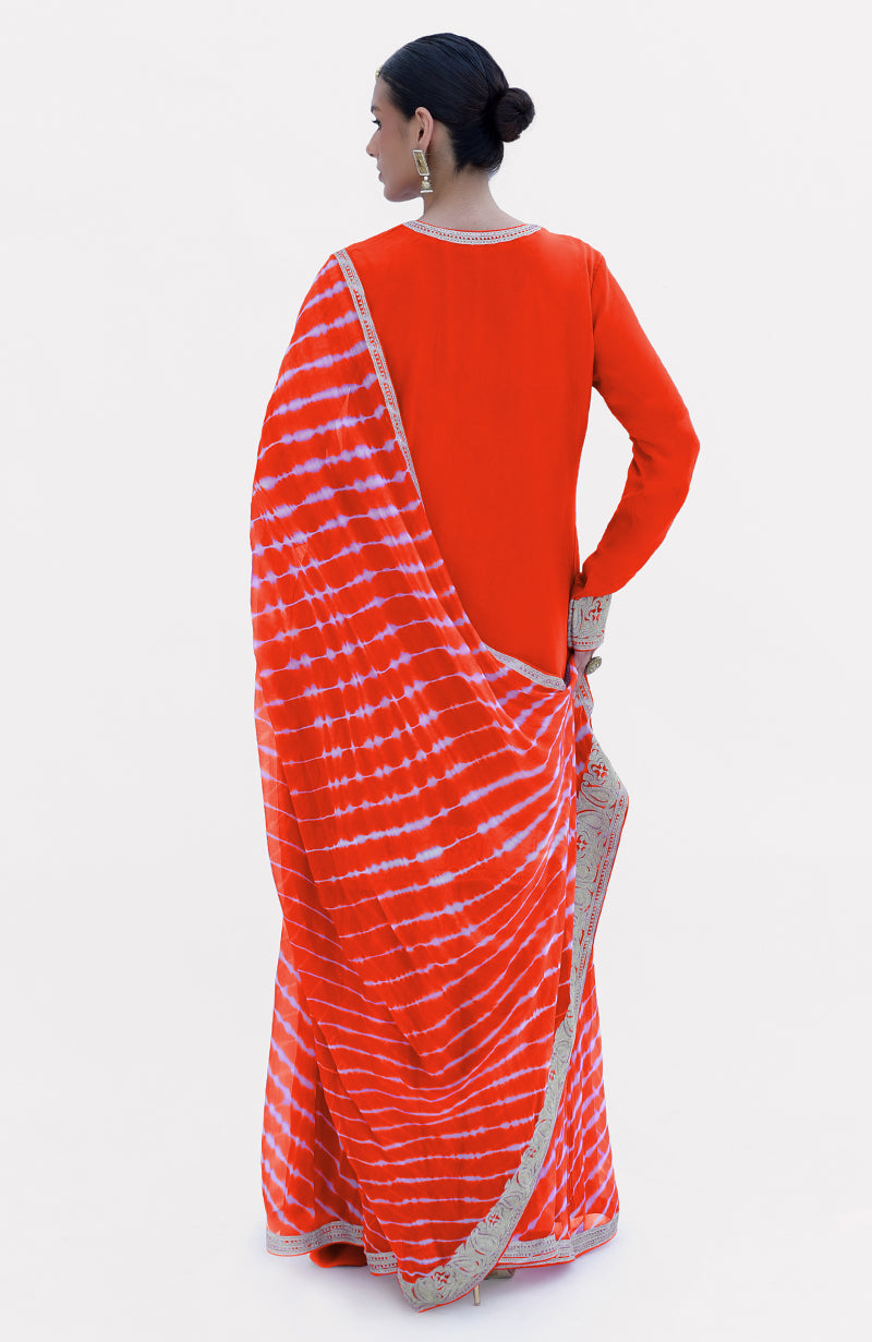 A woman from behind wears a tomato red leheriya tie-dye sharara set with silver tilla embroidery.