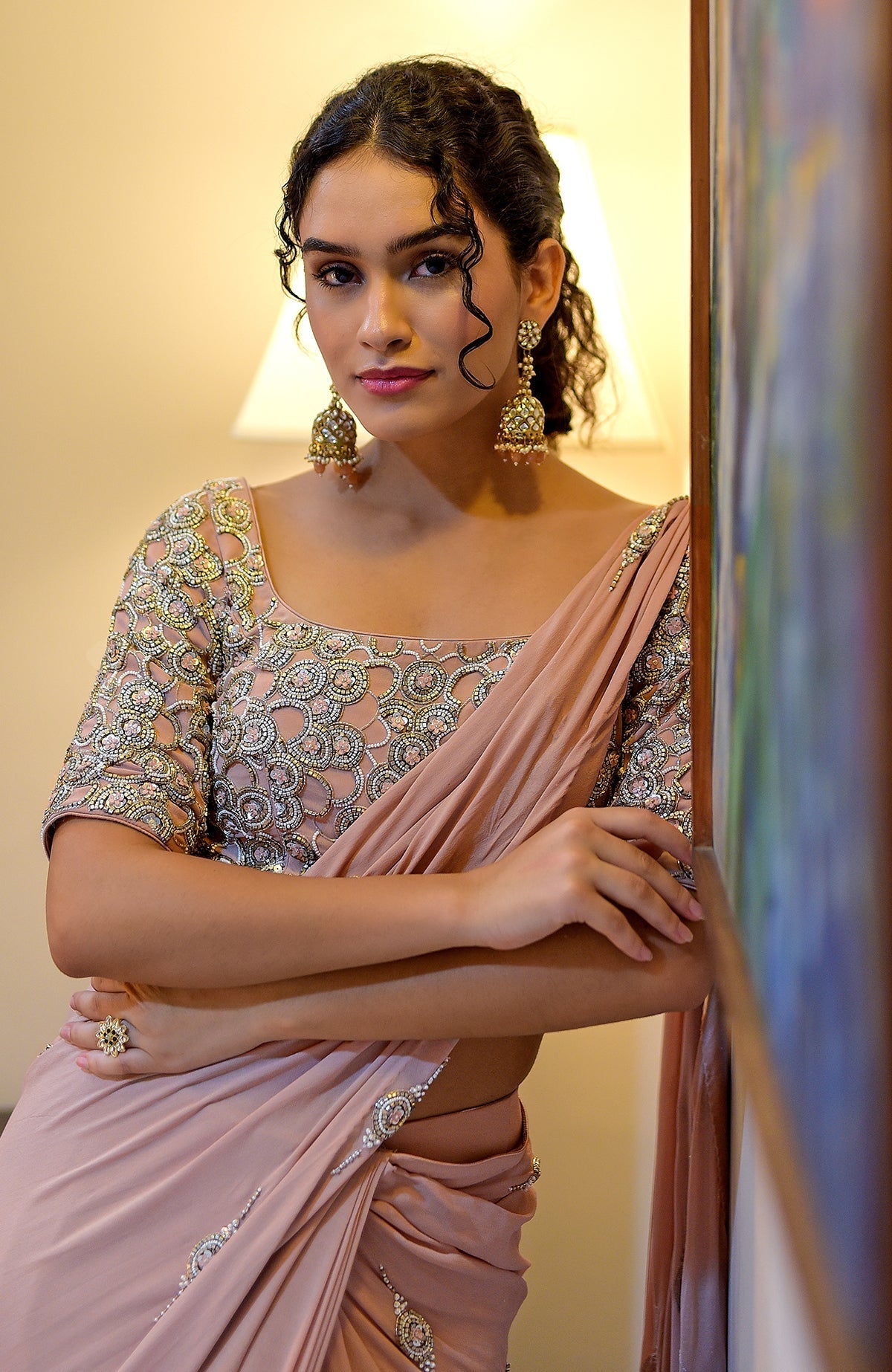 A woman models a nude hand-embroidered pre-draped saree with a matching blouse.