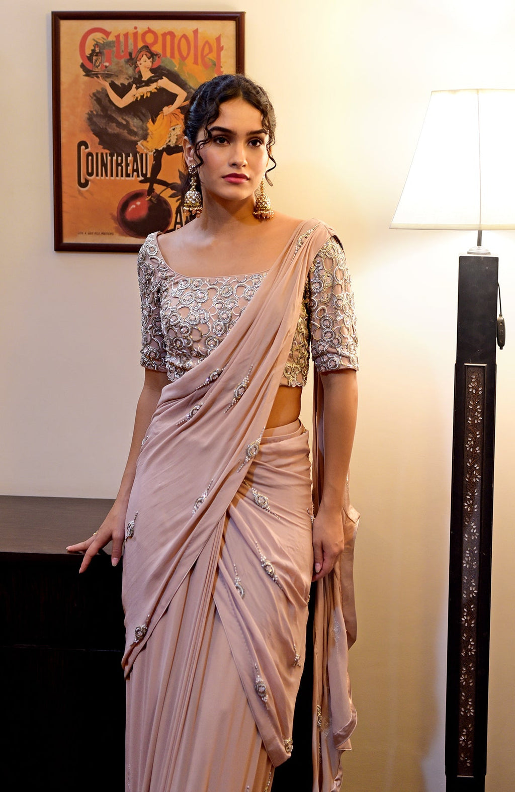 A woman models a nude hand-embroidered pre-draped saree with a matching blouse.