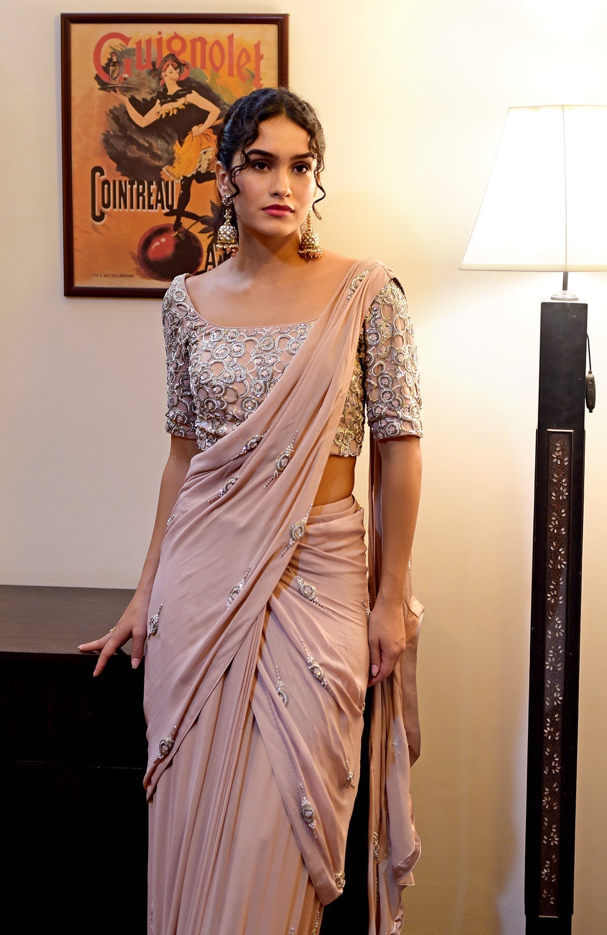 A woman models a nude hand-embroidered pre-draped saree with a matching blouse.