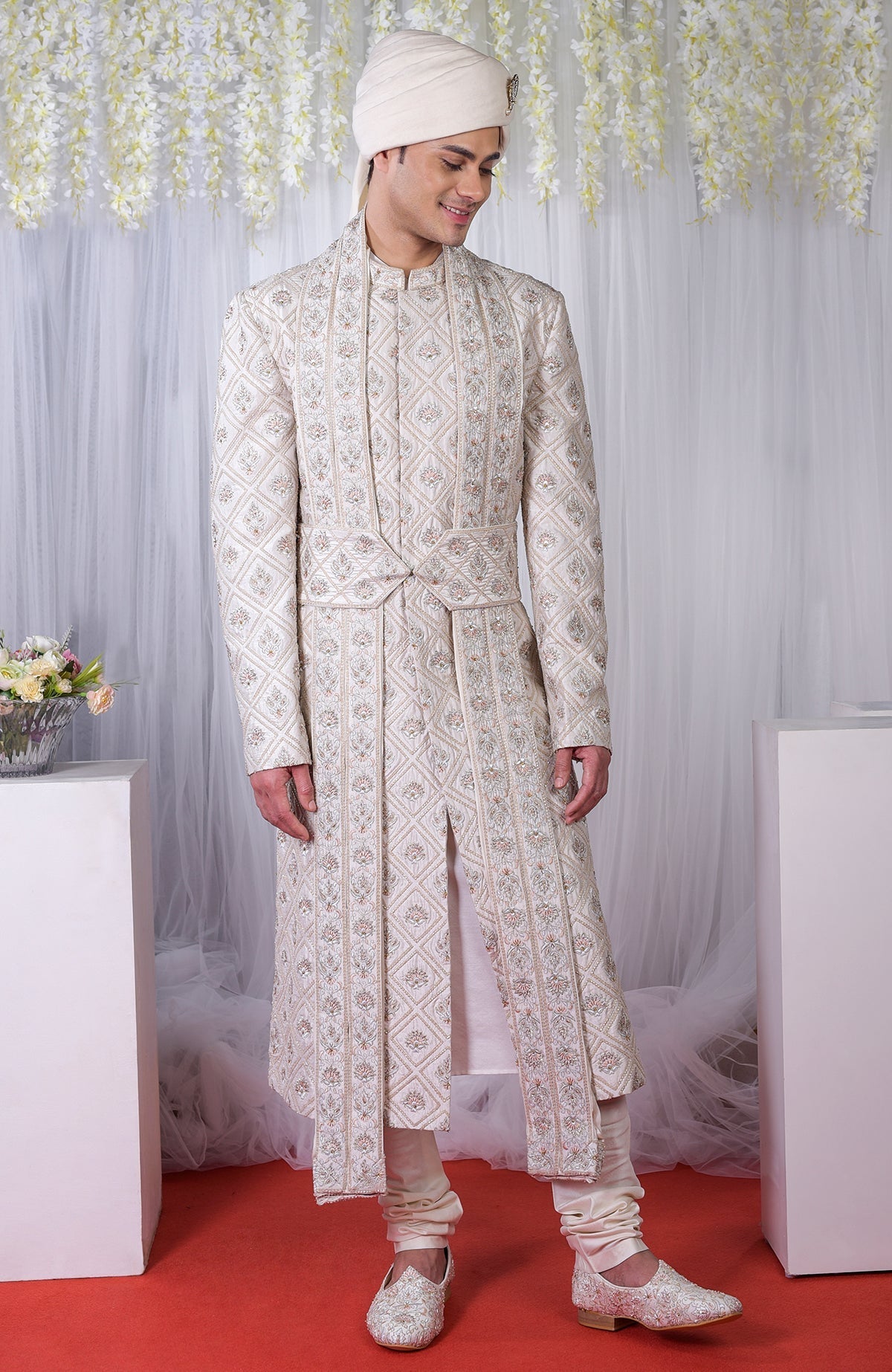 An ivory geometric floral embroidered sherwani set with a matching turban and shoes.