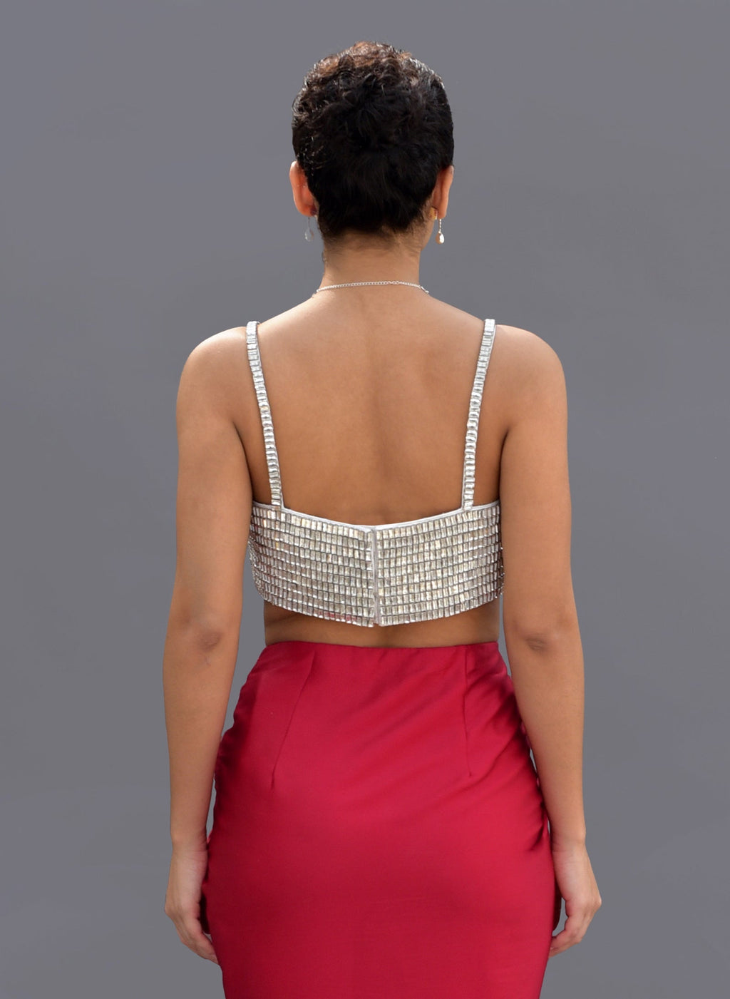 A woman from behind wears a crystal-embroidered bustier and a red skirt.