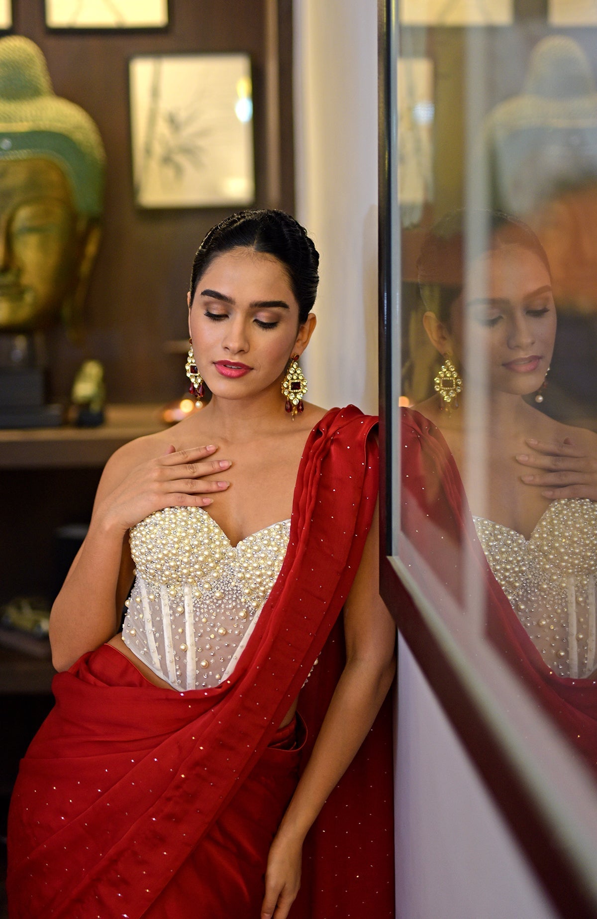 White hand-embroidered corset with a red saree featuring gold sprinkle work.