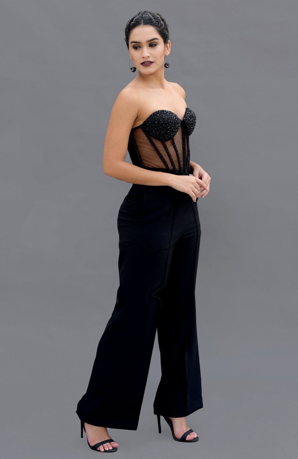 A woman models a black hand-embroidered corset and matching pants set.