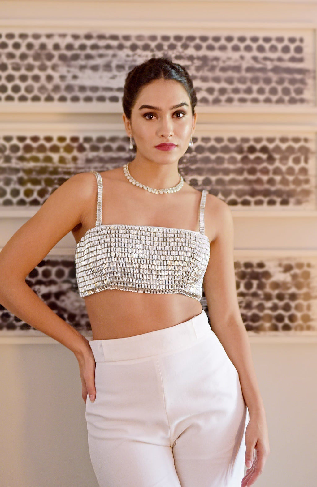A woman models a diamante crystal hand-embroidered bustier and white pants set.