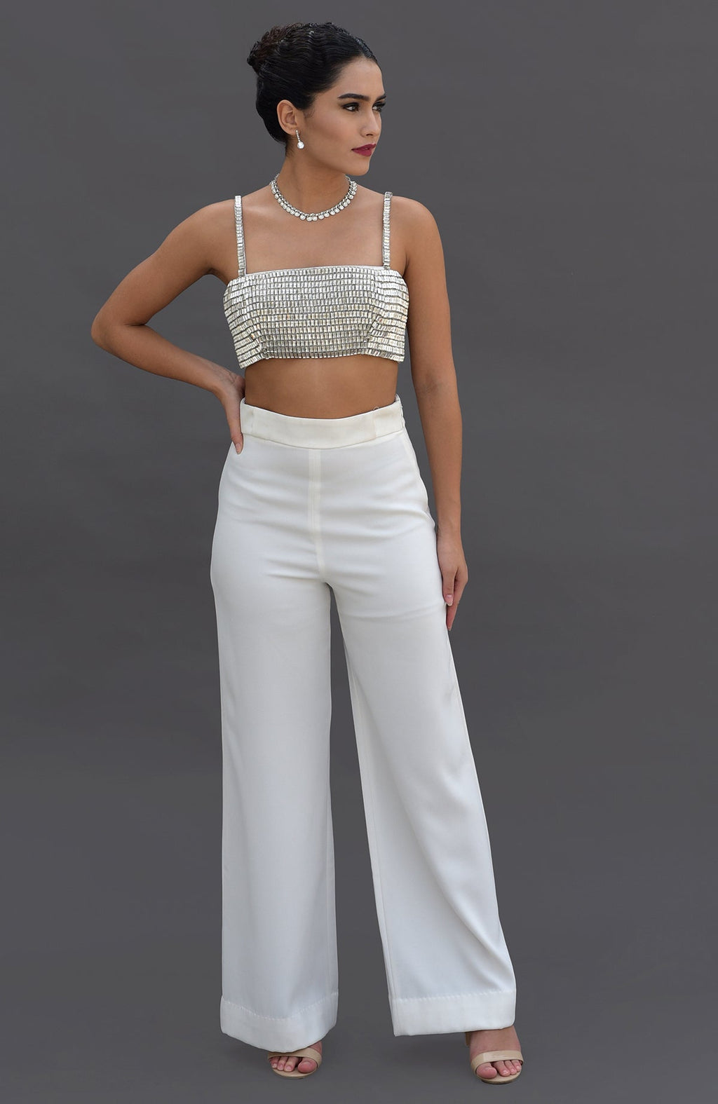 A woman models a white diamante crystal embroidered bustier and matching wide-leg pants.