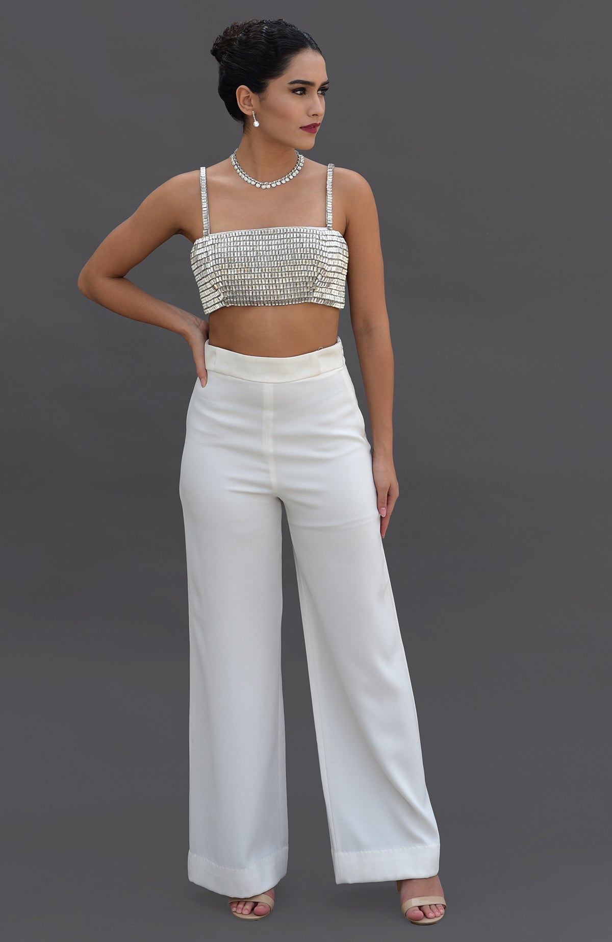 A woman models a white diamante crystal embroidered bustier and matching wide-leg pants.