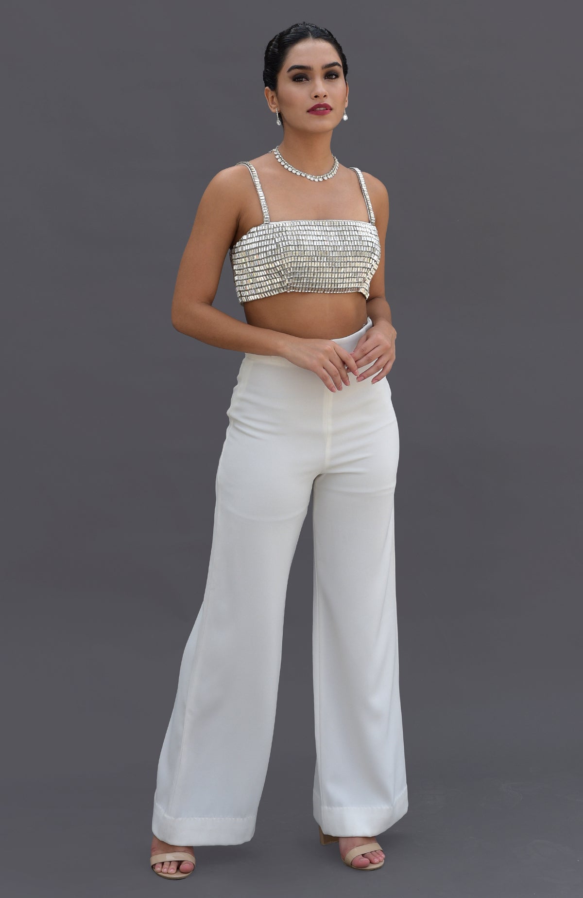 A woman models a diamante crystal hand-embroidered bustier and white pants set.