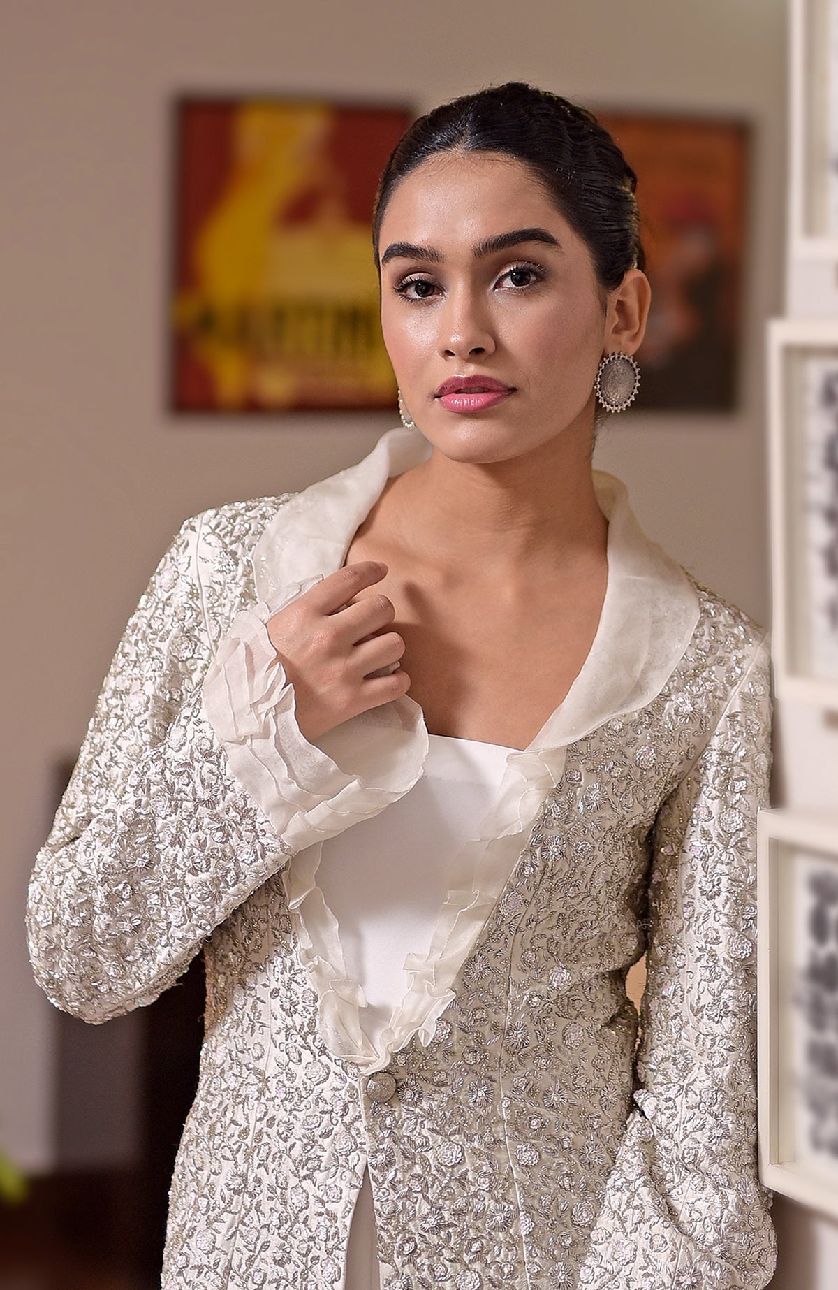 A woman models a white hand-embroidered jacket with a ruffled collar and cuffs.