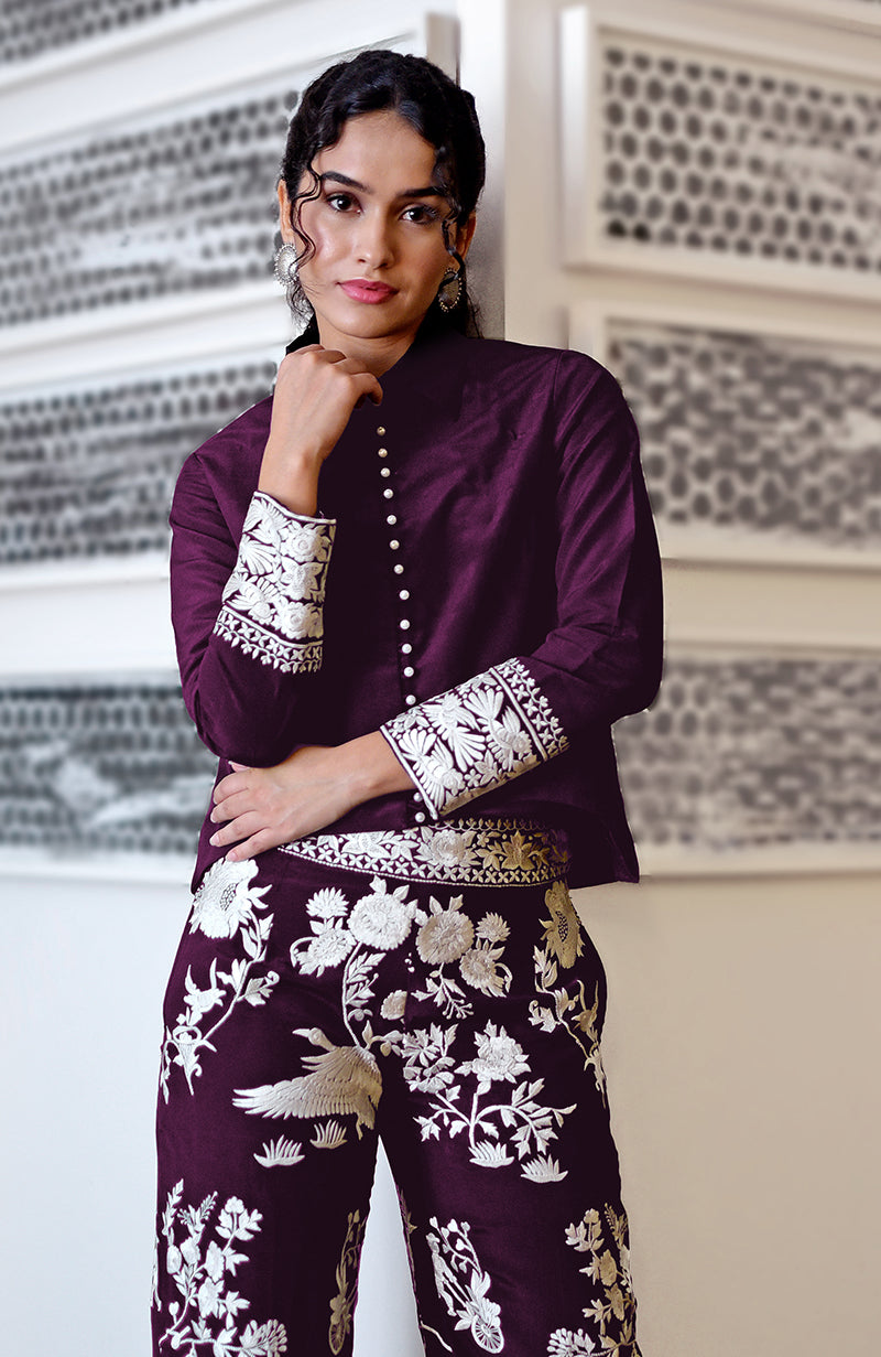 A woman models a plum Parsi Gara embroidered co-ord set with white buttons.