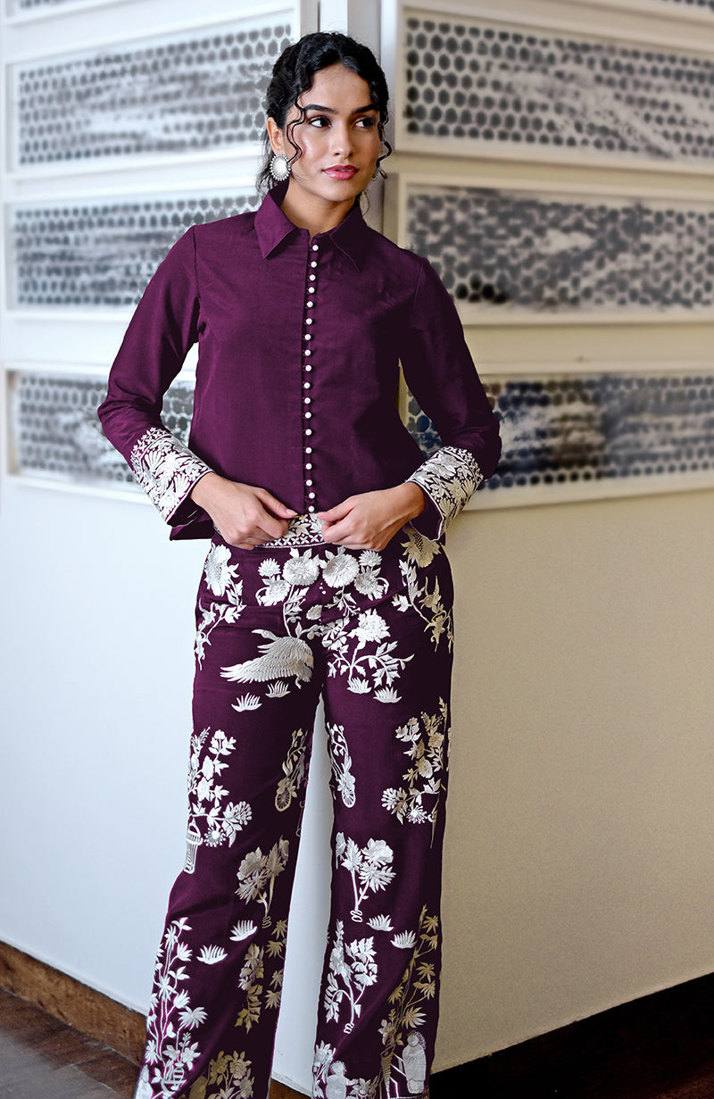 A woman models a plum Parsi Gara embroidered co-ord set with a collared shirt and pants.