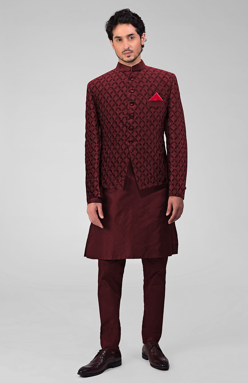 A man models a black chikankari embellished bandhgala jacket set with a red pocket square.