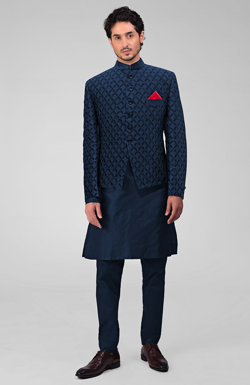 Man in a navy blue chikankari bandhgala jacket, kurta, and pants with brown shoes.