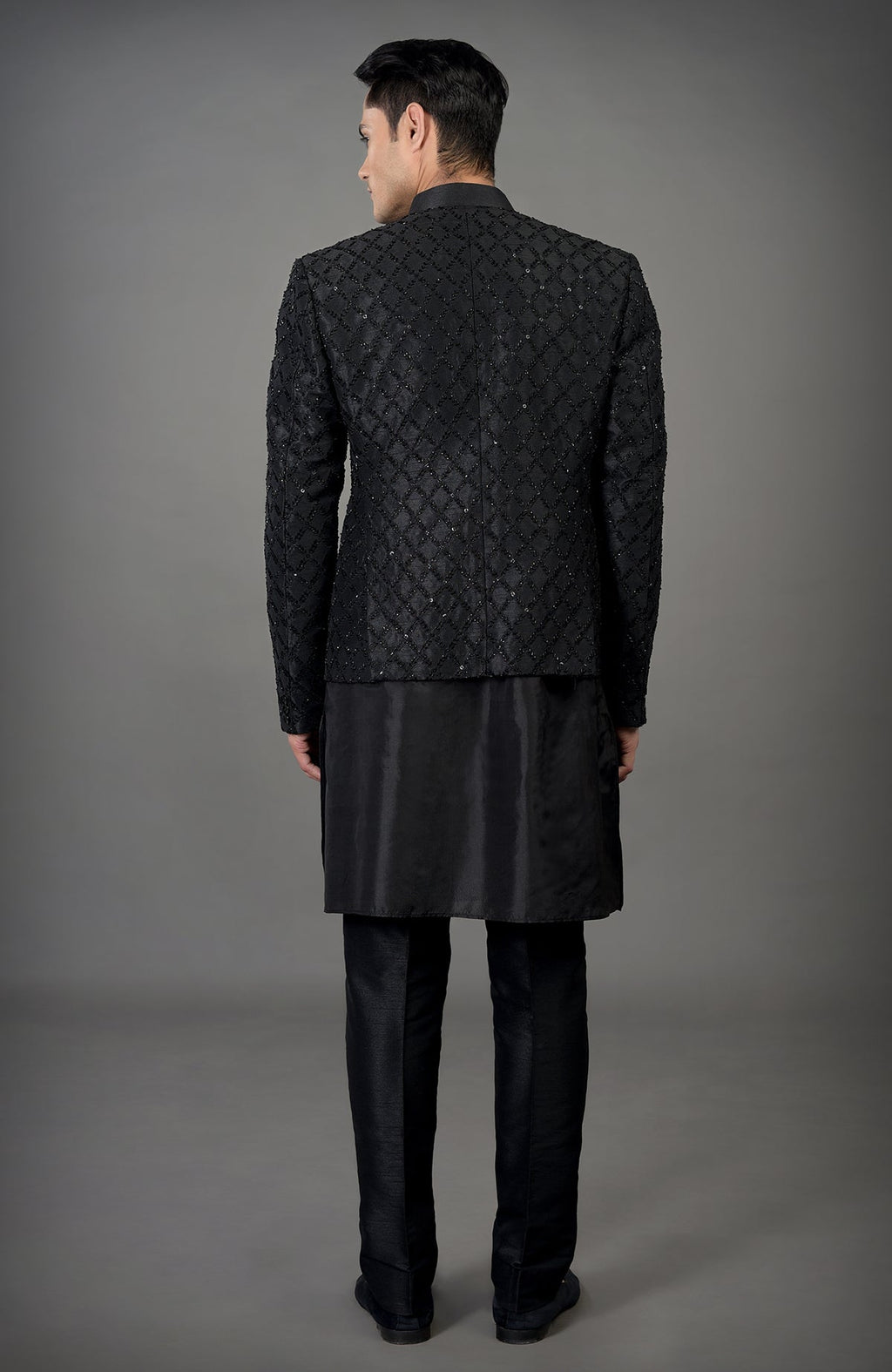 A man from behind wearing a black chikankari embellished bandhgala jacket set.