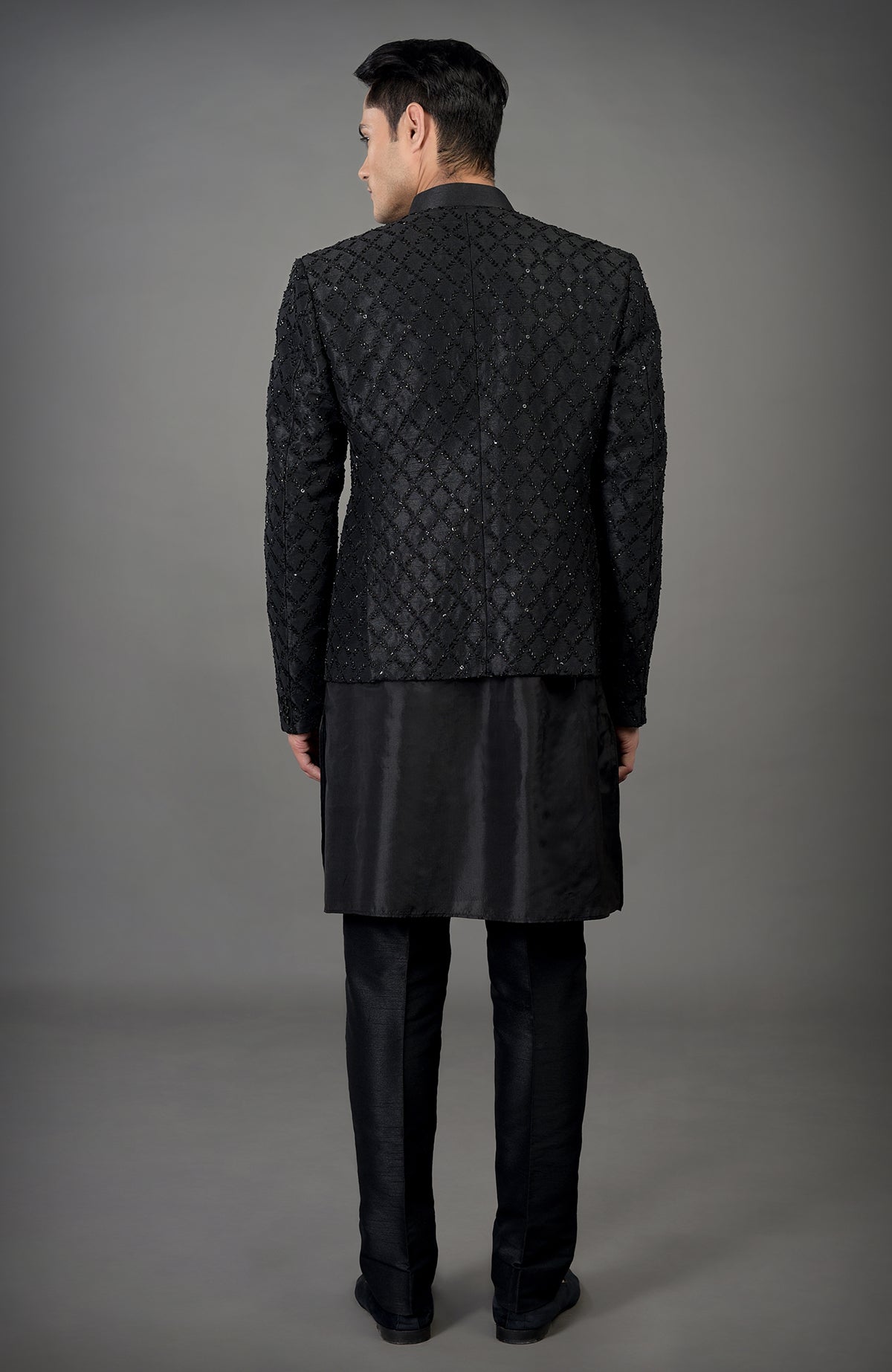 A man from behind wearing a black chikankari embellished bandhgala jacket set.