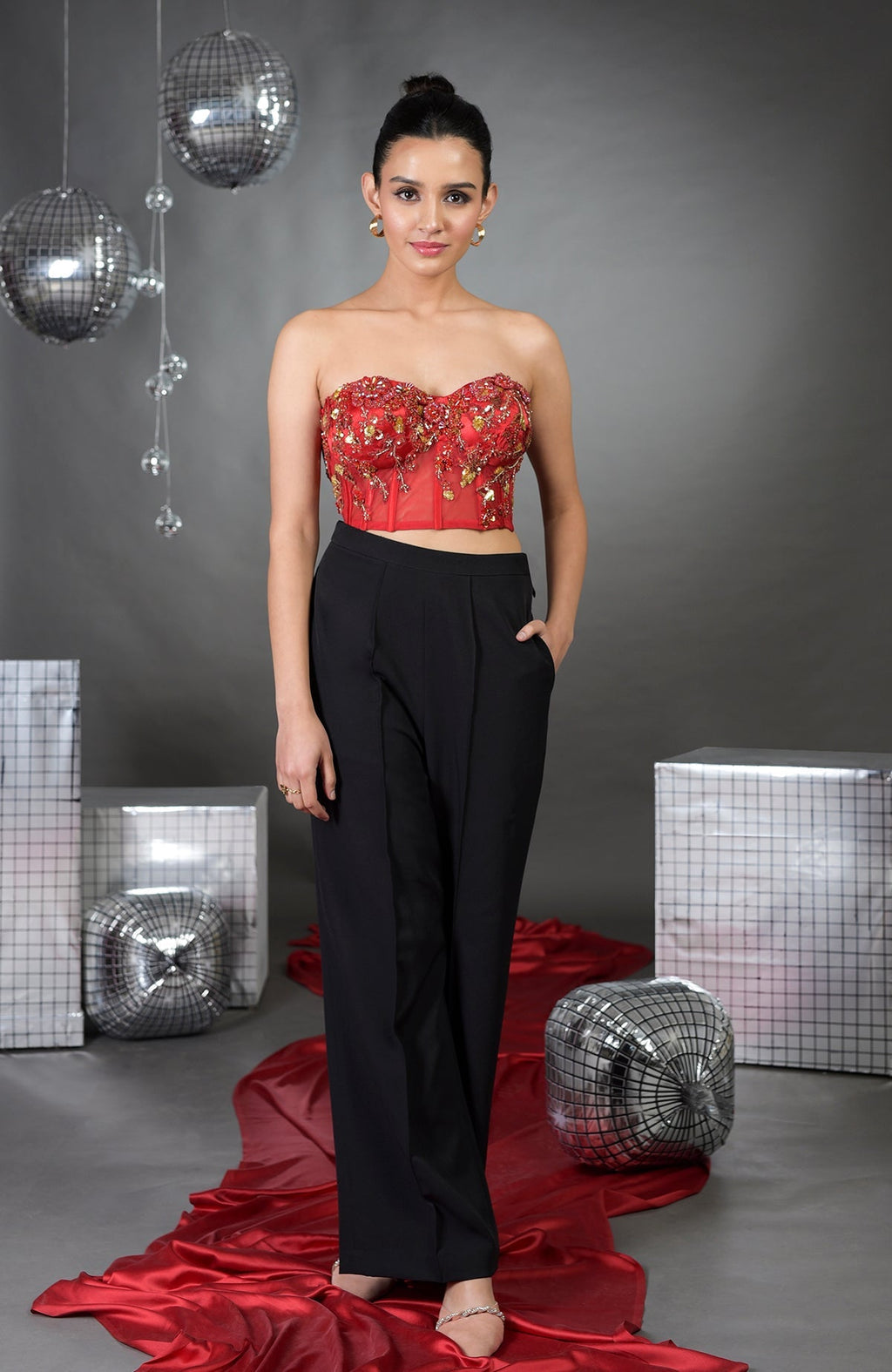 Red floral embroidered corset with black wide-legged pants.