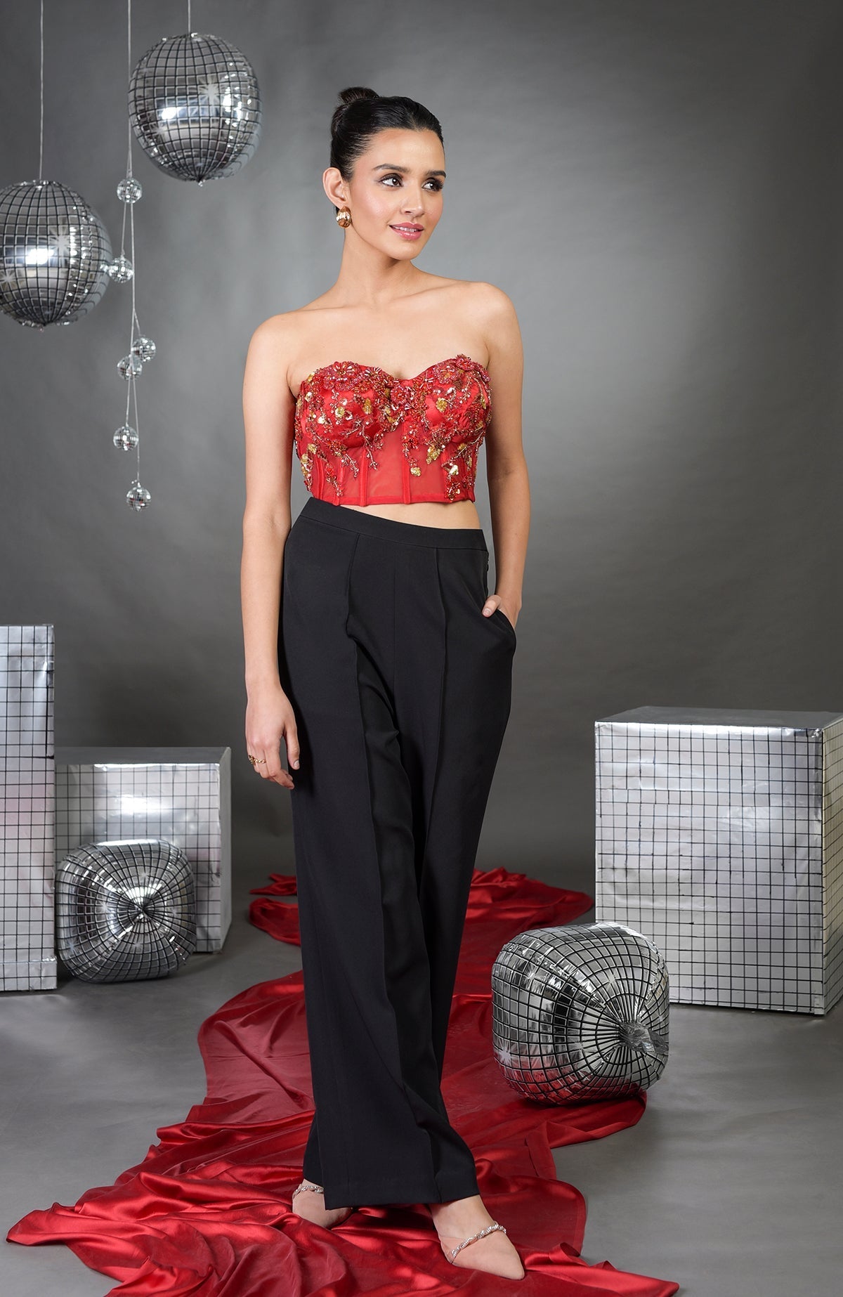 A woman in a red floral embroidered corset and black wide-legged pants.
