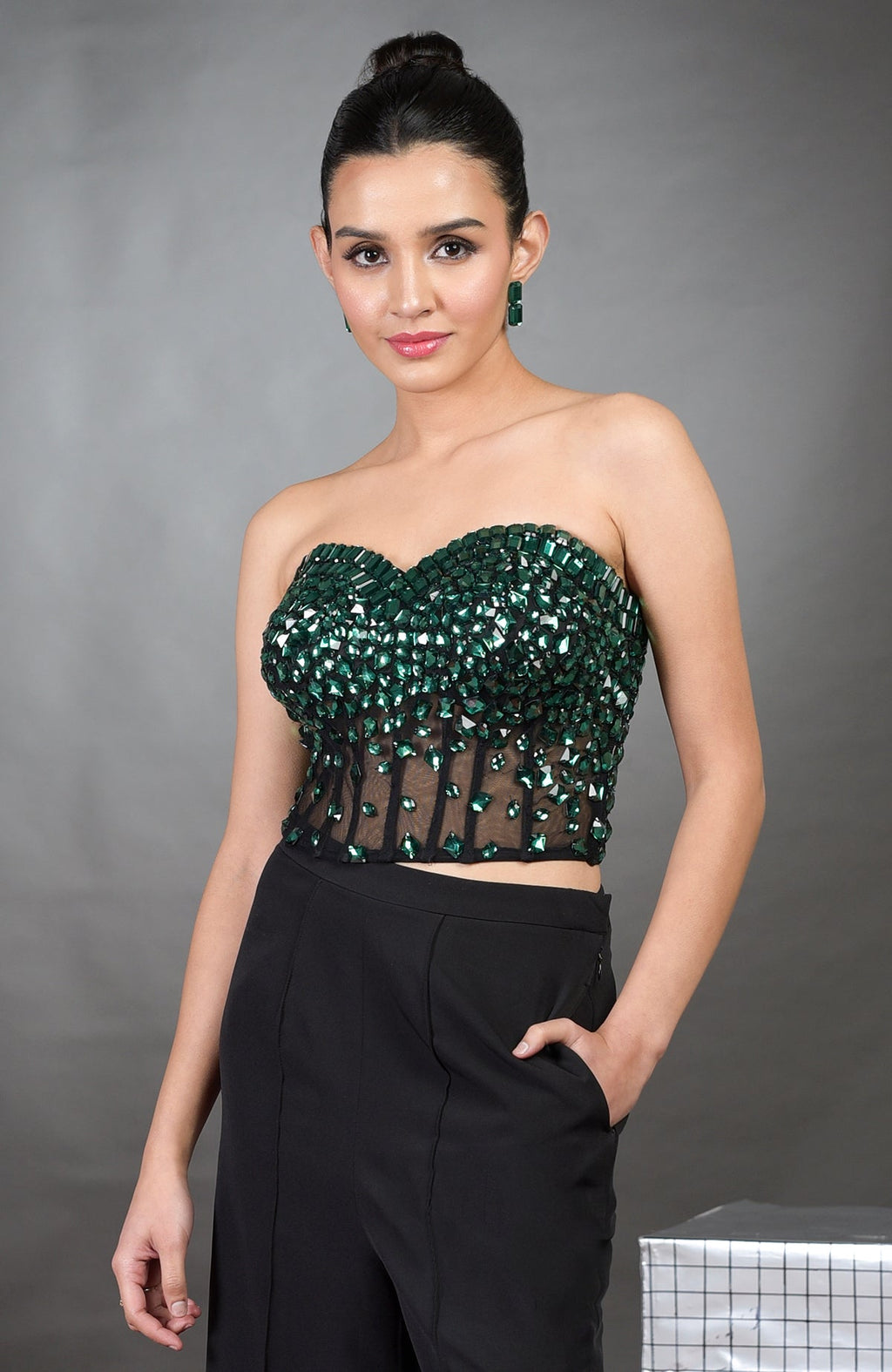A woman models an emerald green hand-embroidered corset and black pants set.