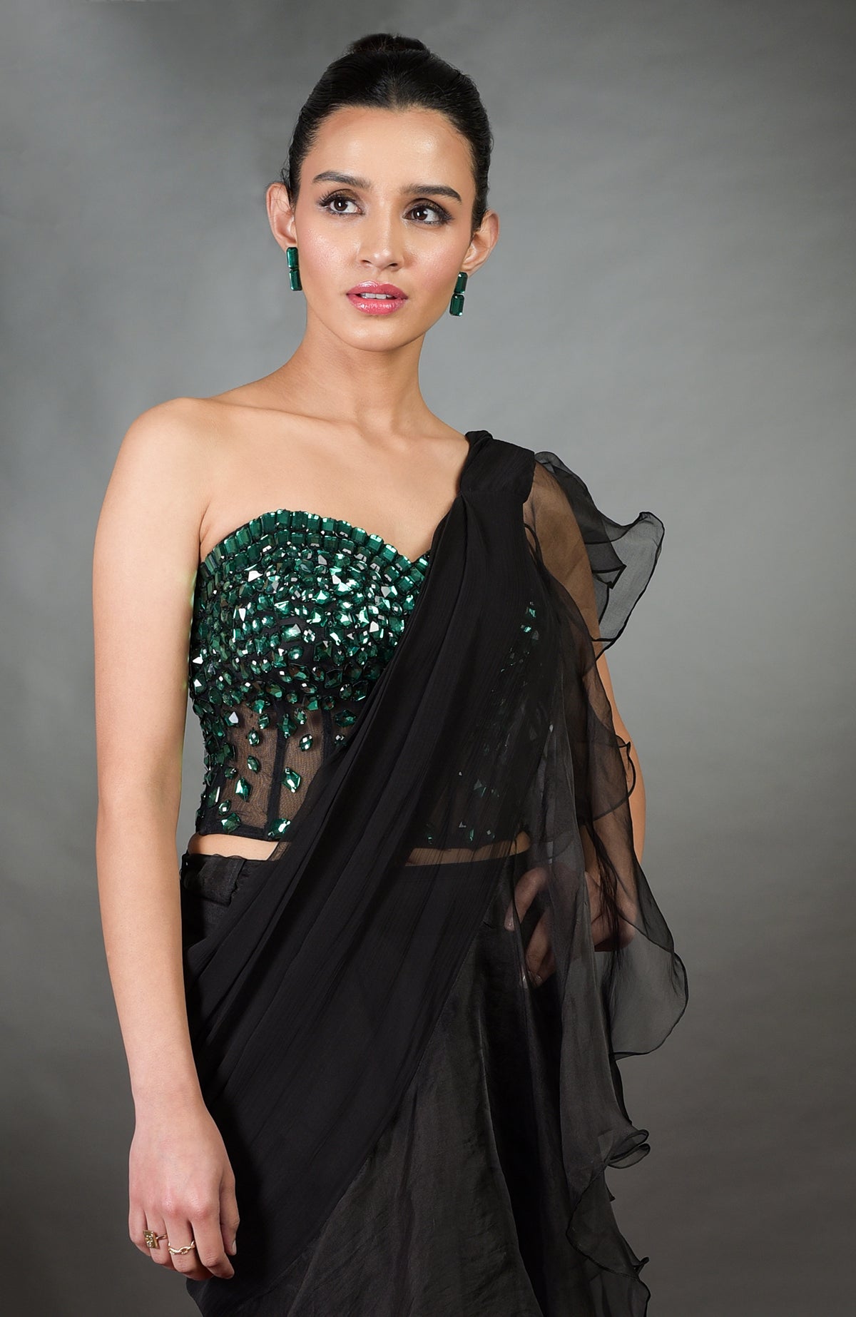 A woman models an emerald green embroidered corset with a black ruffled saree.