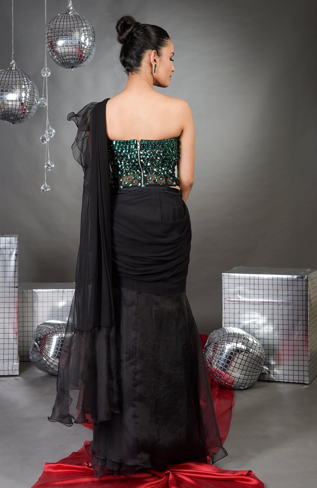 Model in an emerald green corset and black ruffled saree set.