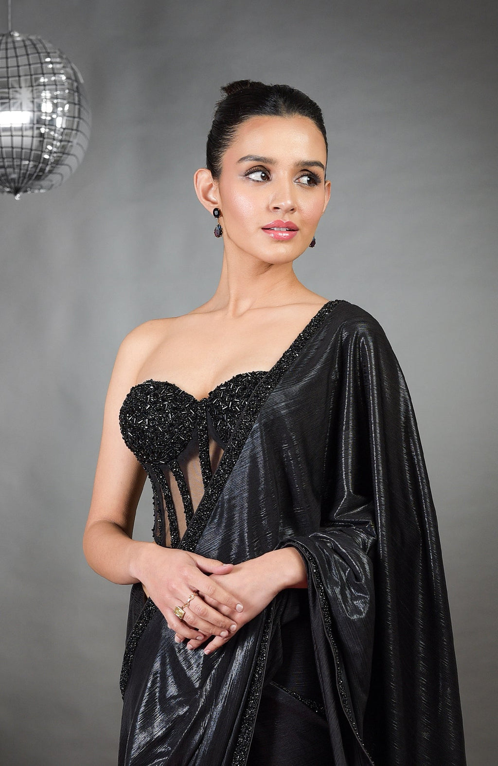 Black hand-embroidered corset saree set with a disco ball in the background.