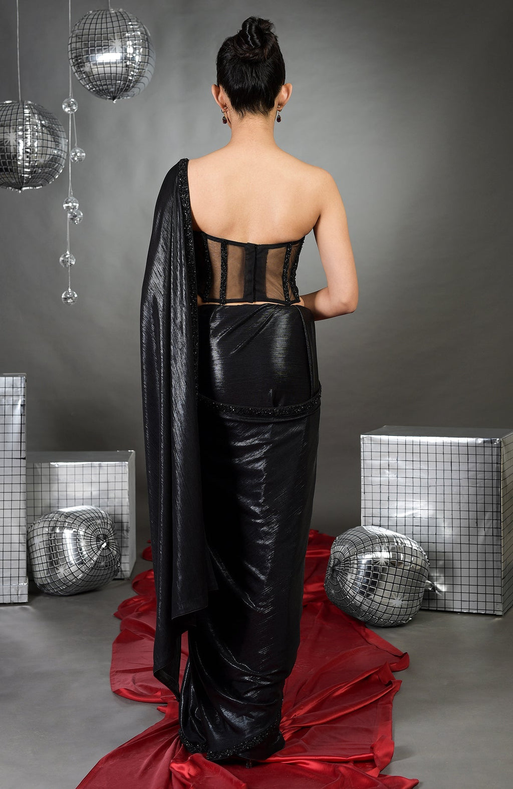 A woman from behind wears a black corset and matching saree with beaded embroidery.