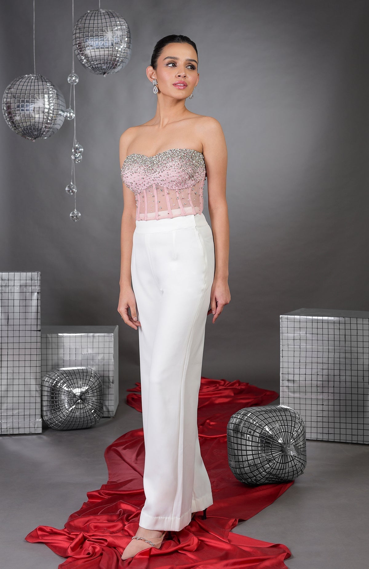 A model wears a pink embroidered corset with white wide-leg pants.