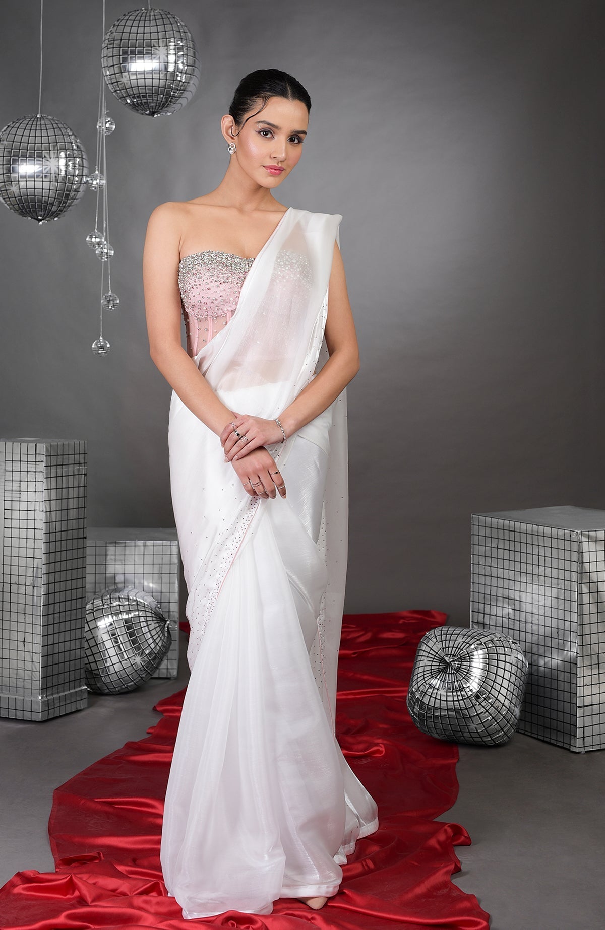A woman models a white saree with a pink embroidered corset.