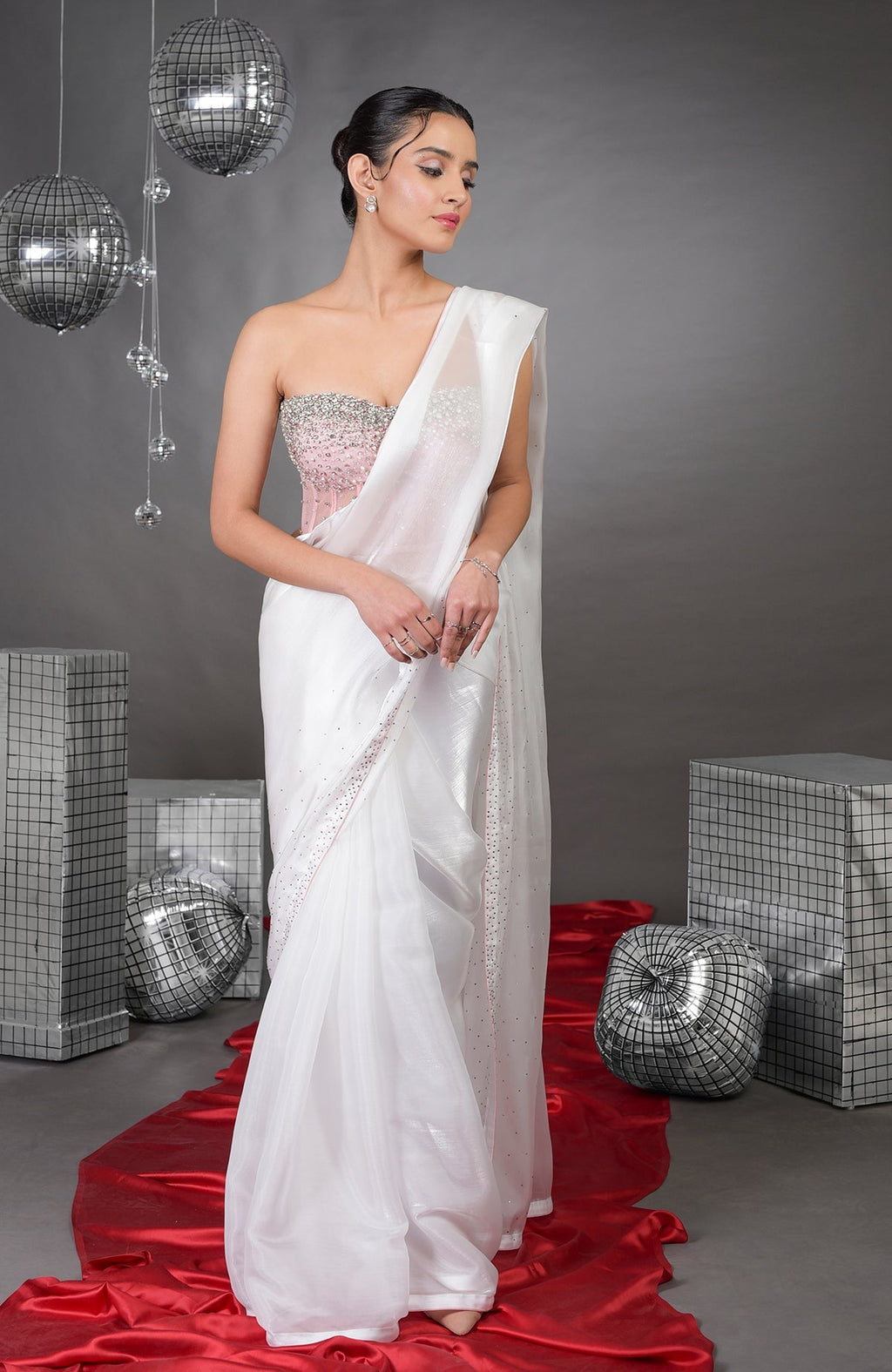 A woman models a white saree with a pink embroidered corset.
