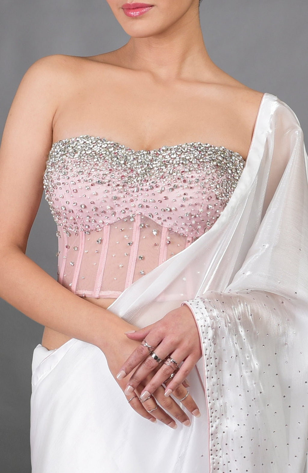 A model wears a pink hand-embroidered corset with a white silver light saree.