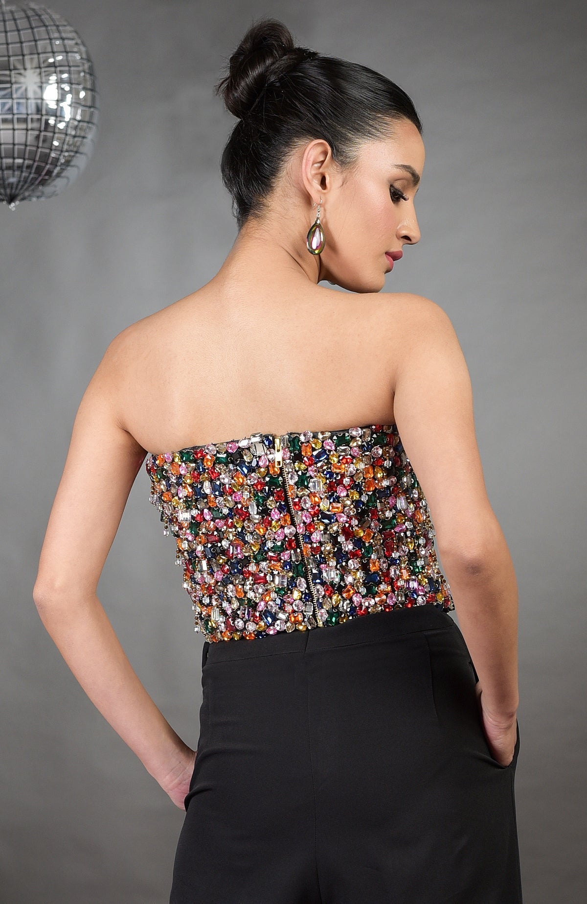 Gemma multi-colored hand-embroidered corset with a back zipper, paired with black pants.
