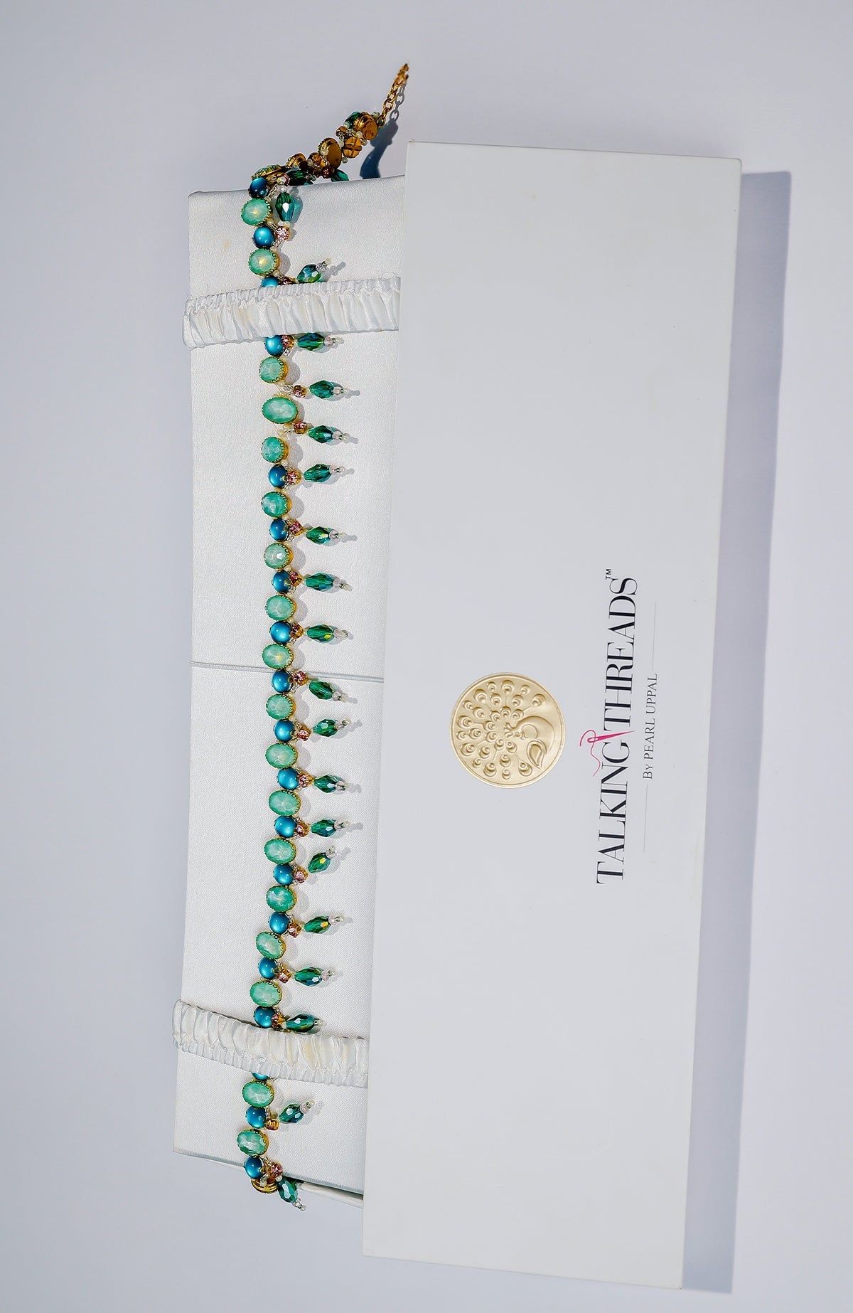 Green jeweled crystal belt in a white luxury accessory box.