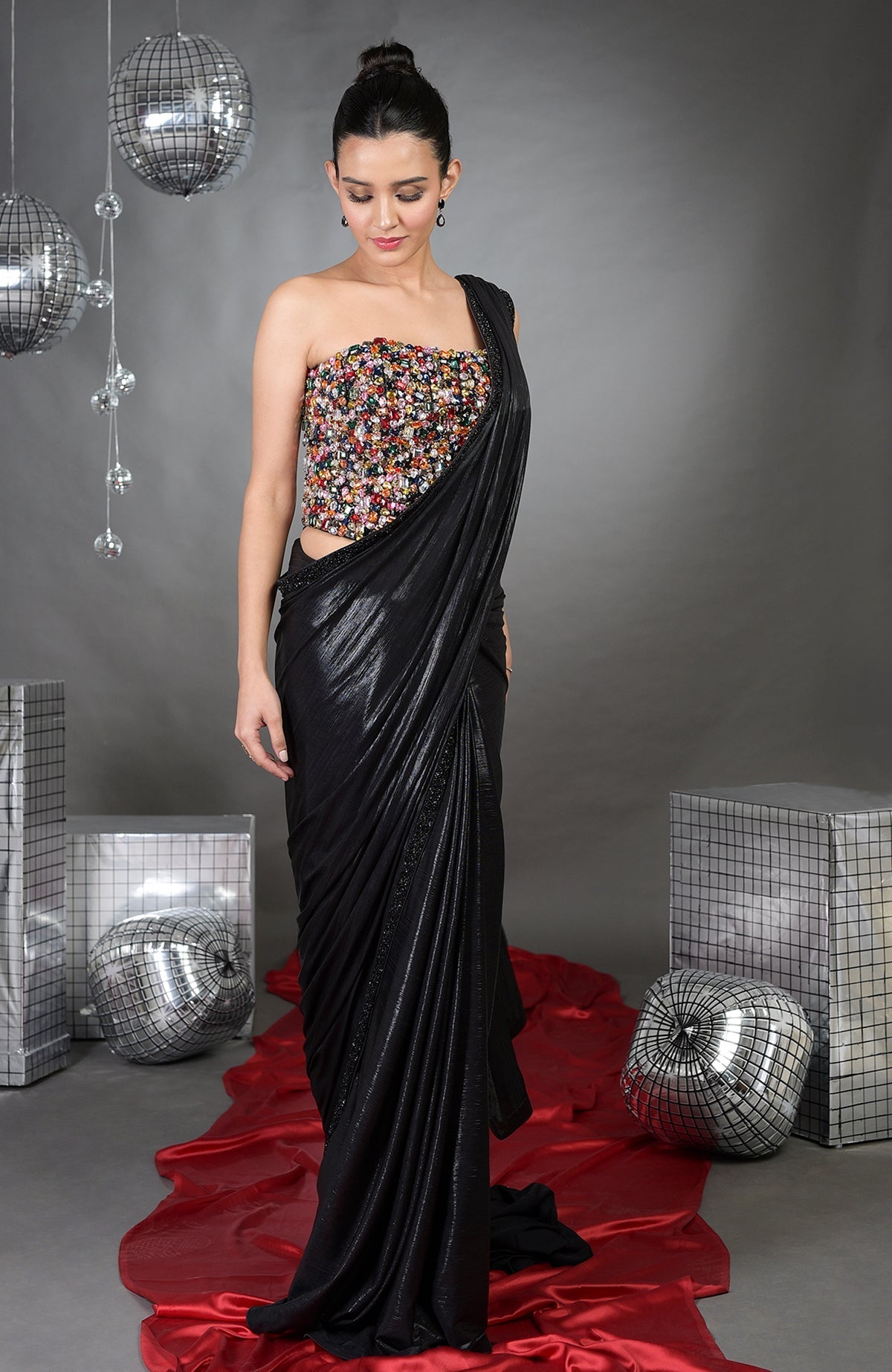 A woman models a black saree with a colorful, embellished strapless top.