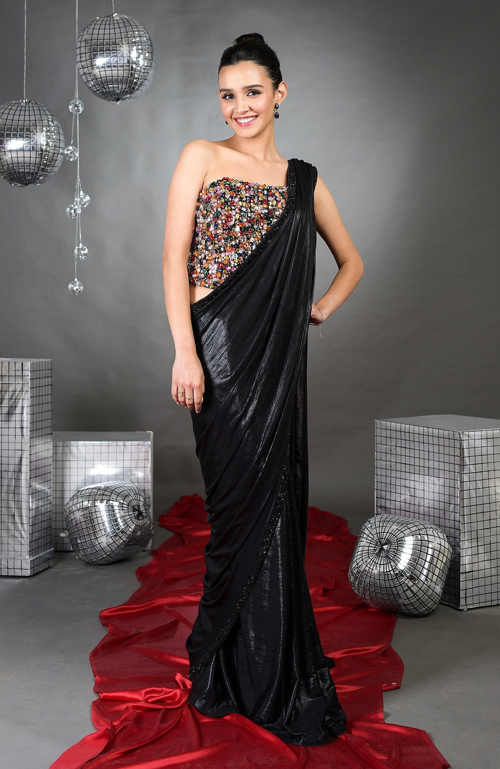 A woman models a black saree with a colorful, embroidered strapless top.