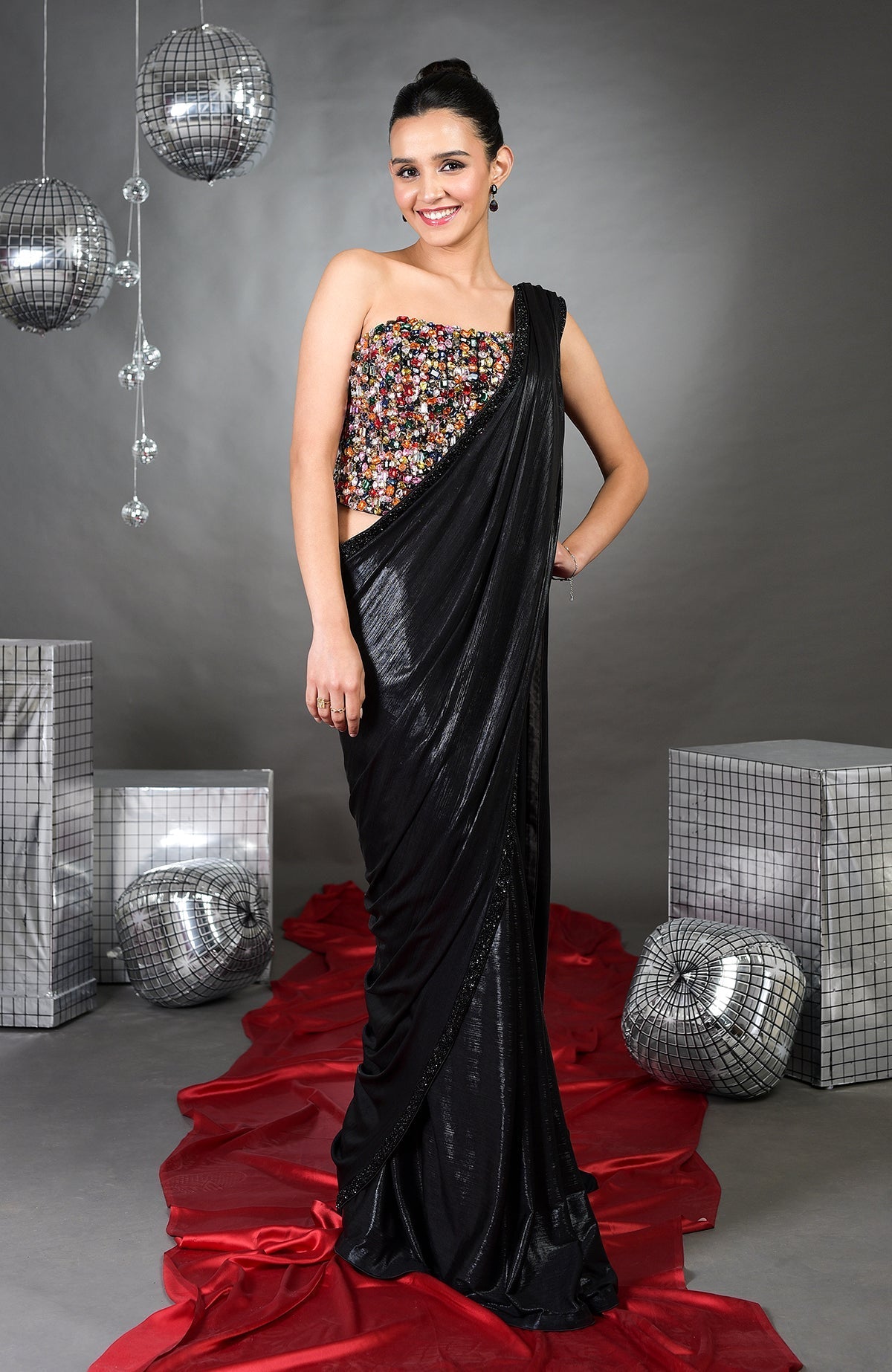 A woman models a black saree with a colorful, embroidered strapless top.