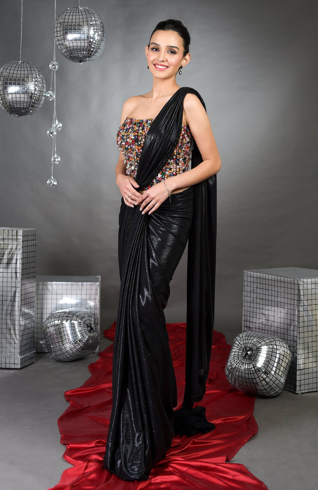A woman models a black saree with a colorful, embellished corset.